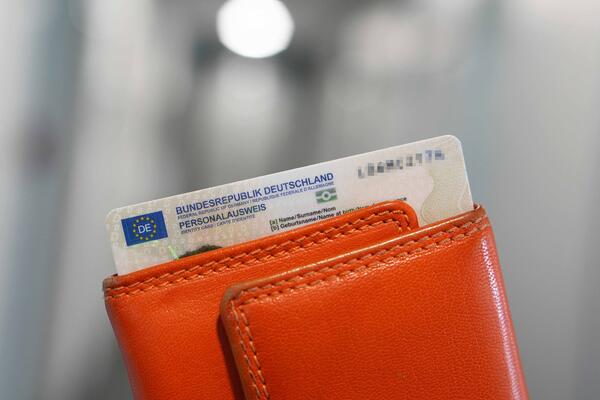 Bild vergr&ouml;&szlig;ern: Ein Personalausweis ragt aus einem orangenen Geldbeutel.