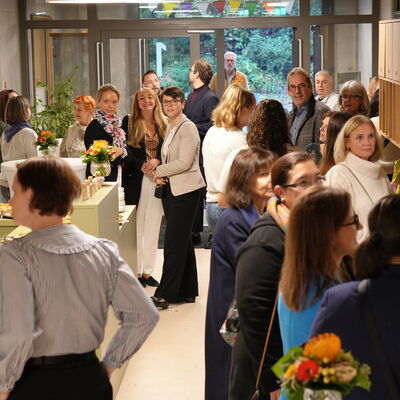 Bild vergr&ouml;&szlig;ern: Menschen stehen im Flur der Kita und unterhalten sich.