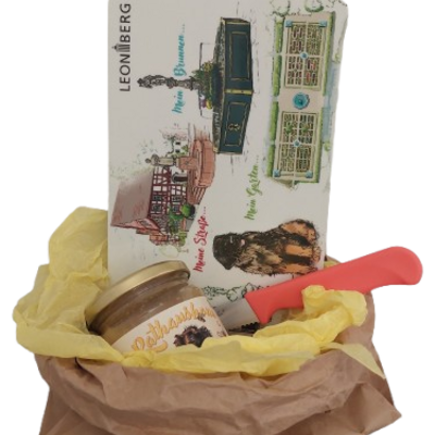 Ein Korb gefüllt mit einem Glas Rathaushonig, einem Vesperbrett und einem Brotmesser. 